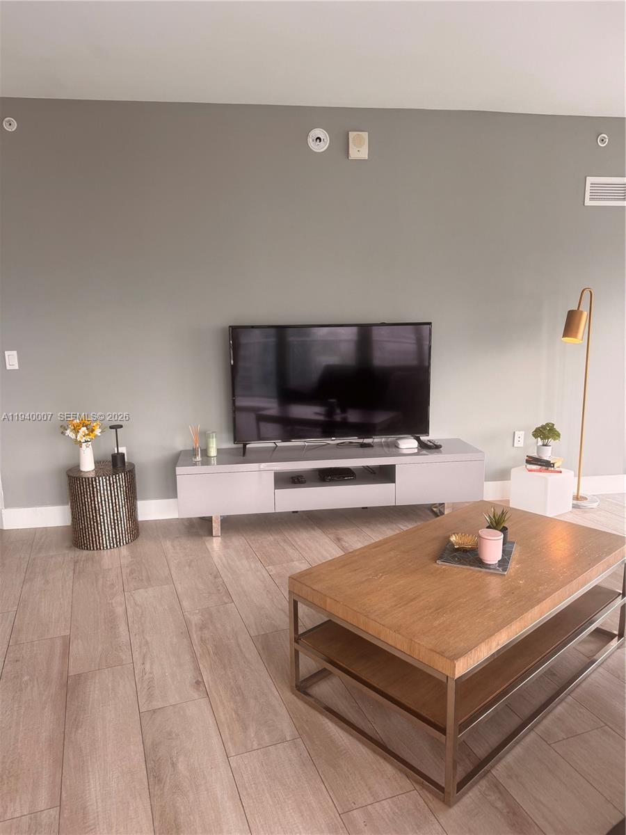 A living room features a grey media console, a wooden coffee table, and a floor lamp — 121 NE 34th St # 1904, Miami FL 33137, MIAMI, FL