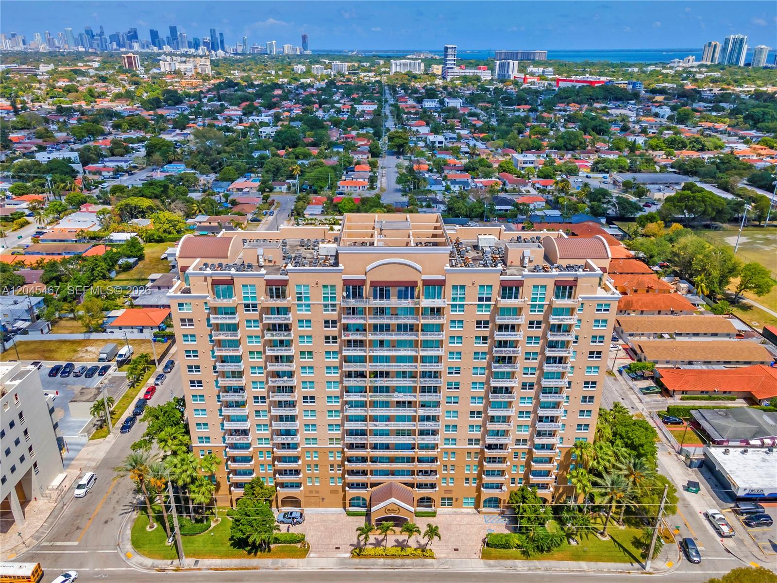 An aerial view of a tall, tan residential apartment building surrounded by suburban houses — 2665 SW 37th Ave # 301, Miami FL 33133, MIAMI, FL
