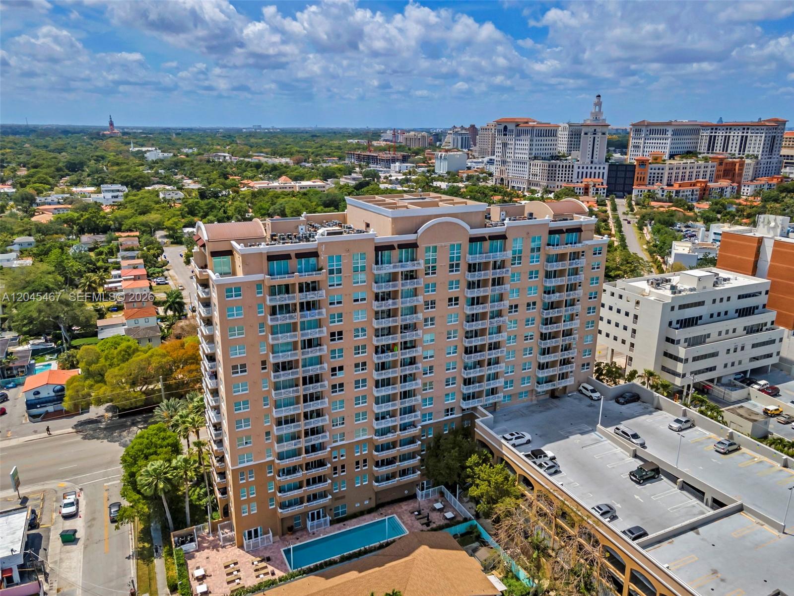 An aerial view shows a multi-story tan apartment building with balconies and an outdoor pool — 2665 SW 37th Ave # 301, Miami FL 33133, MIAMI, FL