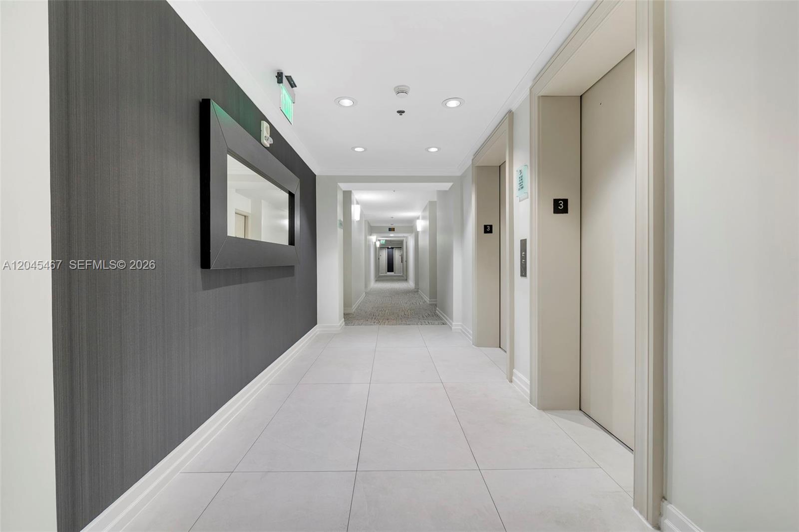 A modern hallway features light tile flooring, a dark accent wall, and elevator doors — 2665 SW 37th Ave # 301, Miami FL 33133, MIAMI, FL