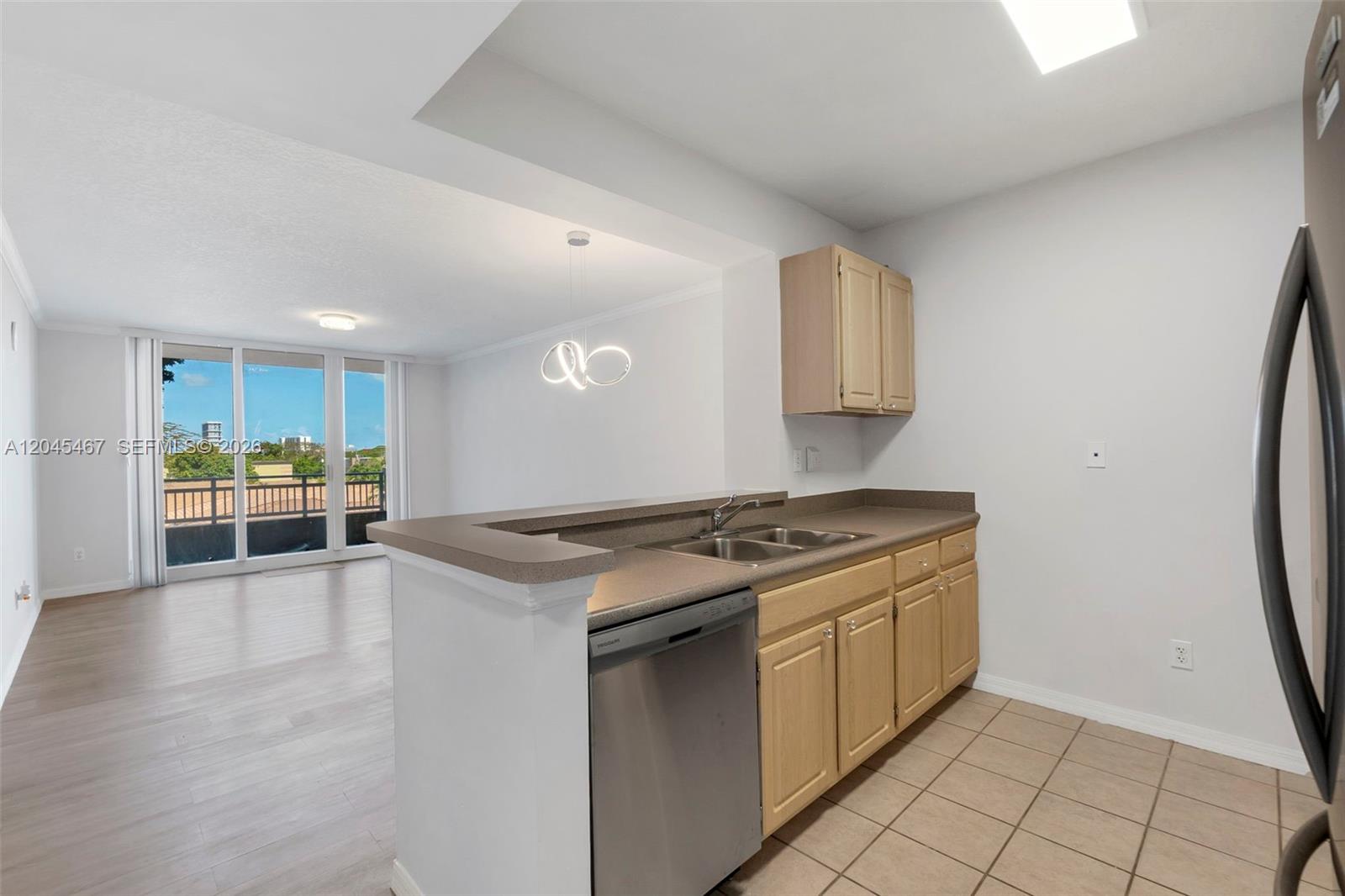 A kitchen with light wood cabinets and a breakfast bar overlooks a living area — 2665 SW 37th Ave # 301, Miami FL 33133, MIAMI, FL