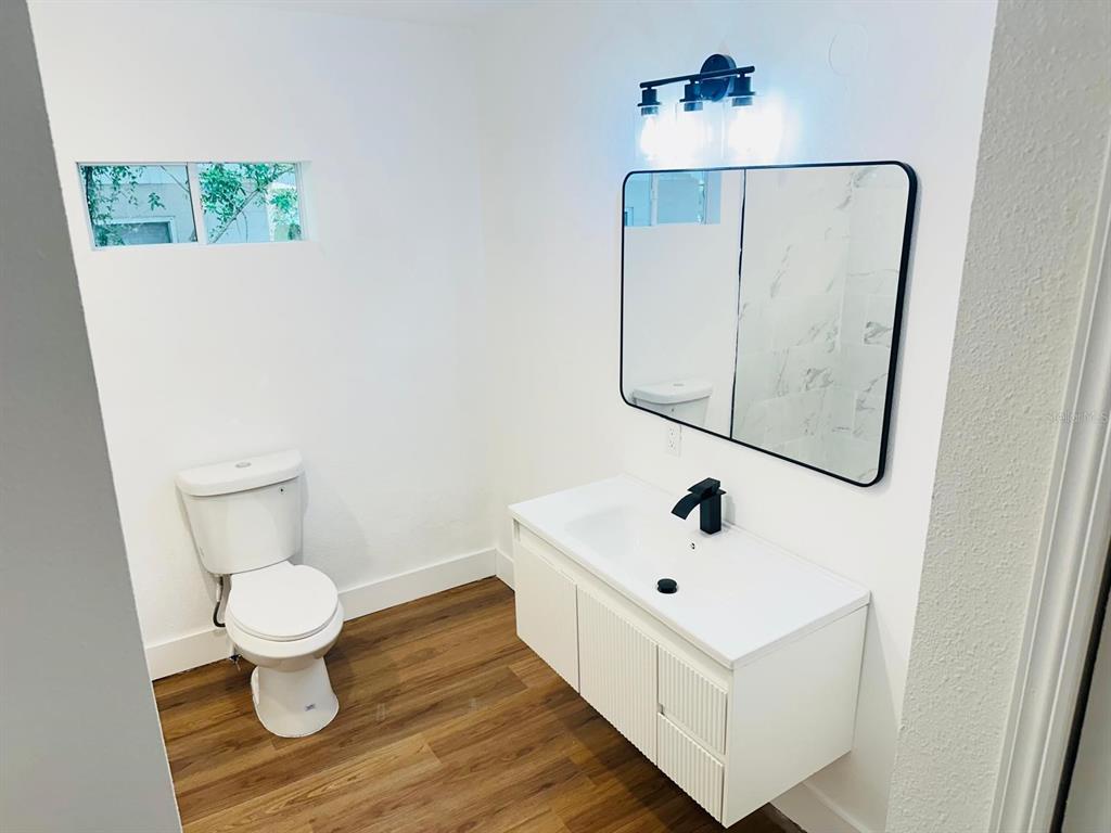 A bathroom features a white floating vanity, a black-framed mirror, and a white toilet — 5621 LEJEUNE DRIVE, ORLANDO, FL