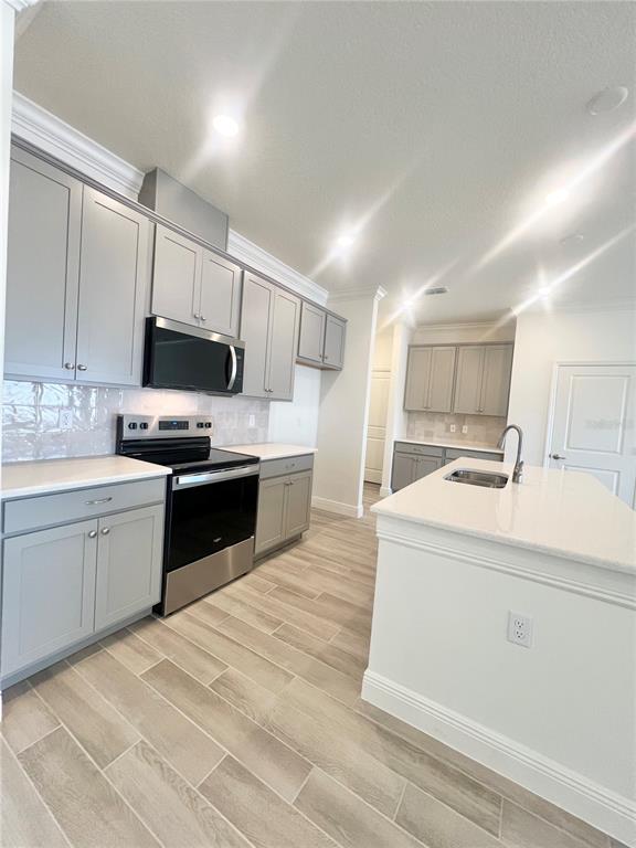 A kitchen features light gray cabinets, stainless steel appliances, a center island, and tile flooring — 31 FALLEN OAK LANE, PALM COAST, FL
