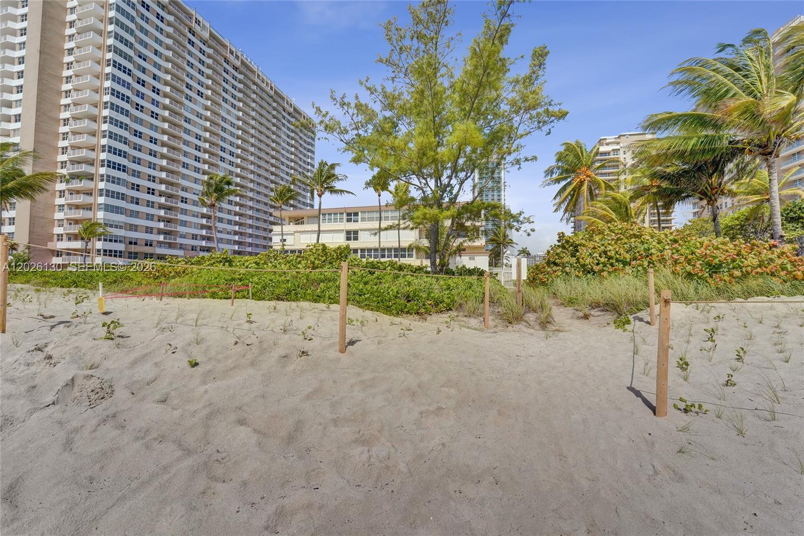 A sandy beach path leads toward a low-rise building and a tall residential tower — 1936 S Ocean Dr # 4C, Hallandale Beach FL 33009, HALLANDALE BEACH, FL