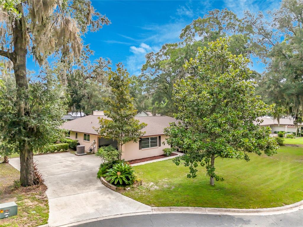 A single-story house with a concrete driveway, a front lawn, and surrounding mature trees — 3944 NW 40TH COURT, GAINESVILLE, FL