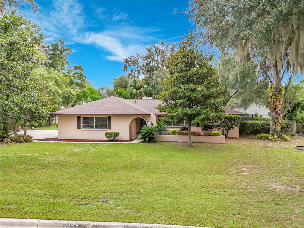 A single-story ranch-style house with a tan exterior, dark roof, and a large front lawn — 3944 NW 40TH COURT, GAINESVILLE, FL