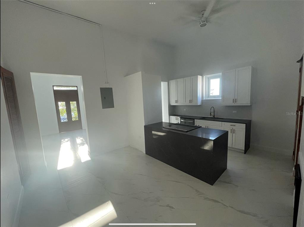 A kitchen features white cabinets, a dark island, and light-colored tile flooring — 9 DEL MERCADO UNIT 3, SAN JUAN, PR