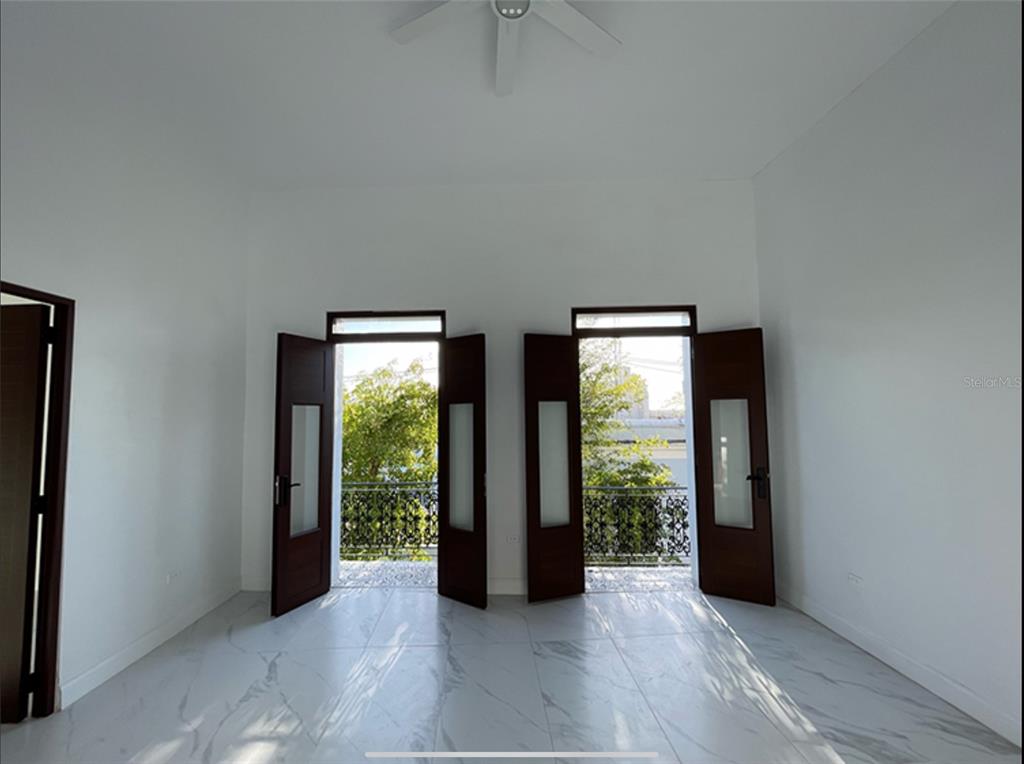 An empty room with white walls, marble-look tile floors, and two sets of open balcony doors — 9 DEL MERCADO UNIT 3, SAN JUAN, PR