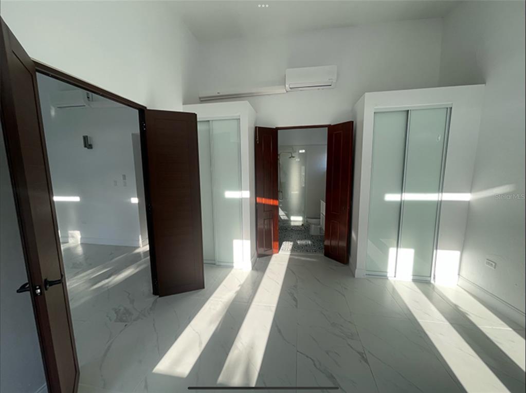 A bedroom with white marble-look tile floors, two white sliding-door closets, and an attached bathroom — 9 DEL MERCADO UNIT 3, SAN JUAN, PR