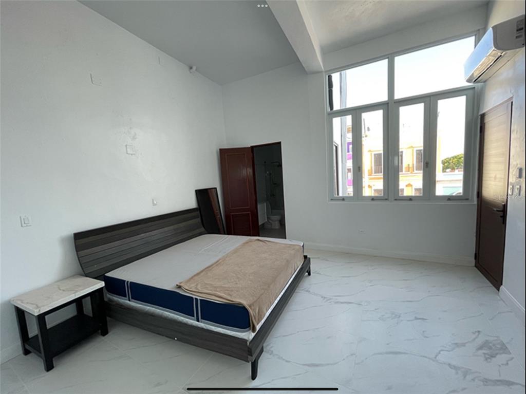 A bedroom with white walls, marble-look tile flooring, a bed, and large windows — 9 DEL MERCADO UNIT 3, SAN JUAN, PR