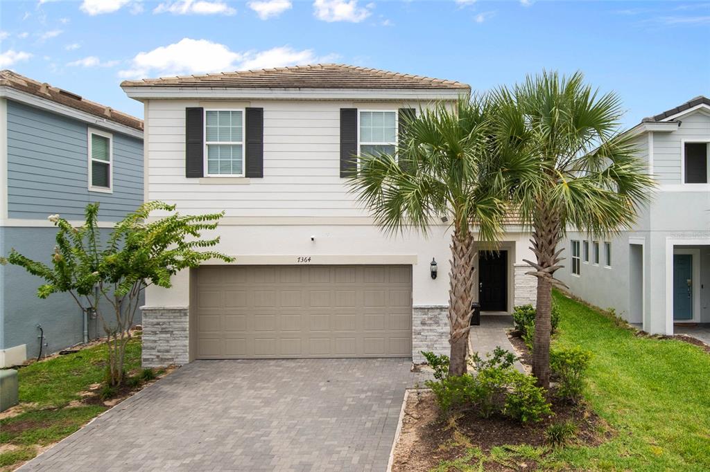 A two-story house with white siding, a two-car garage, and a paved driveway — 7364 OAKMOSS LOOP, DAVENPORT, FL