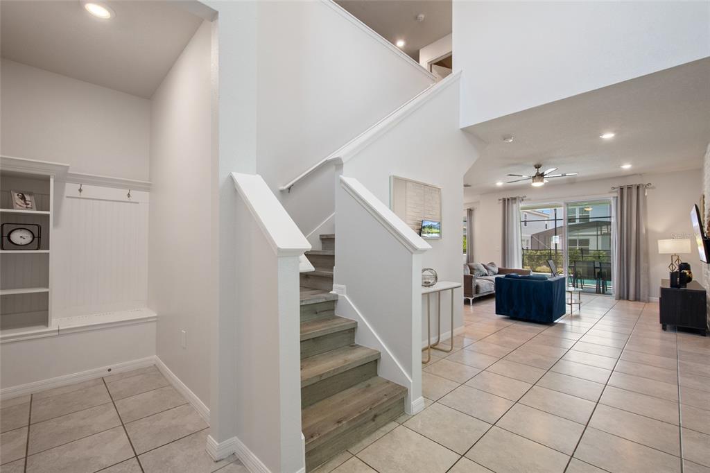 An entryway with a built-in bench and staircase leads to an open-concept living area — 7364 OAKMOSS LOOP, DAVENPORT, FL