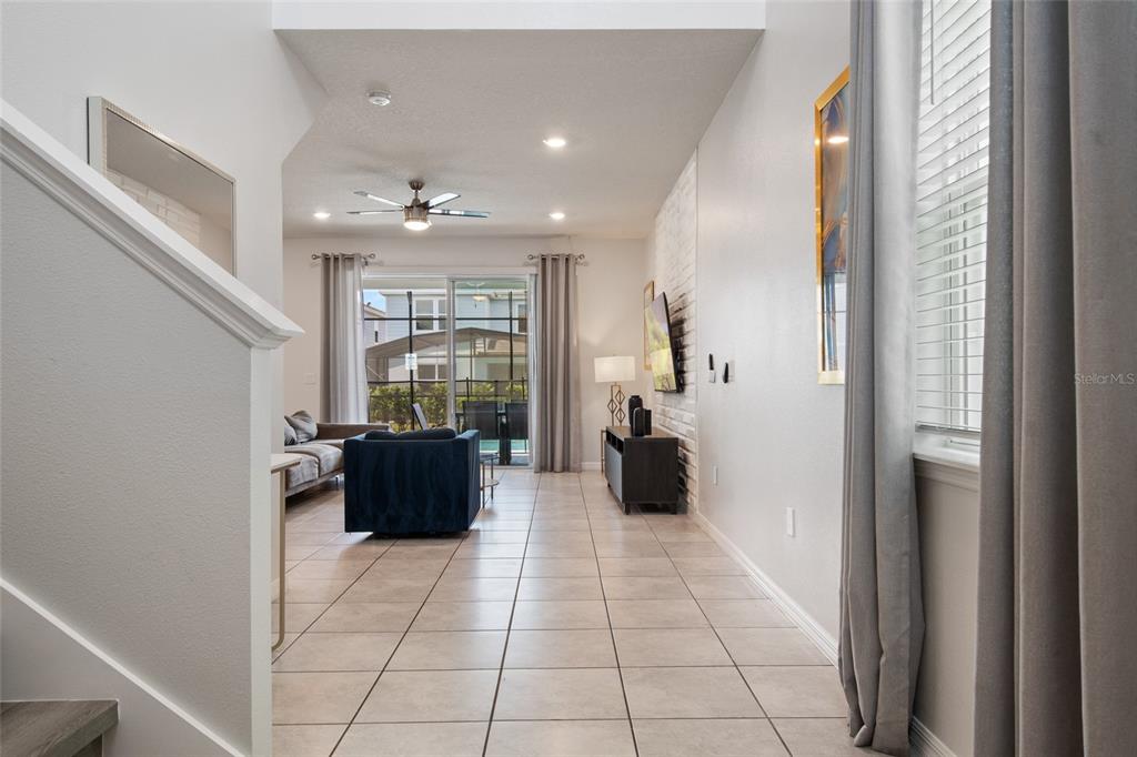 A living room with tile floors, a white brick wall, and sliding glass patio doors — 7364 OAKMOSS LOOP, DAVENPORT, FL