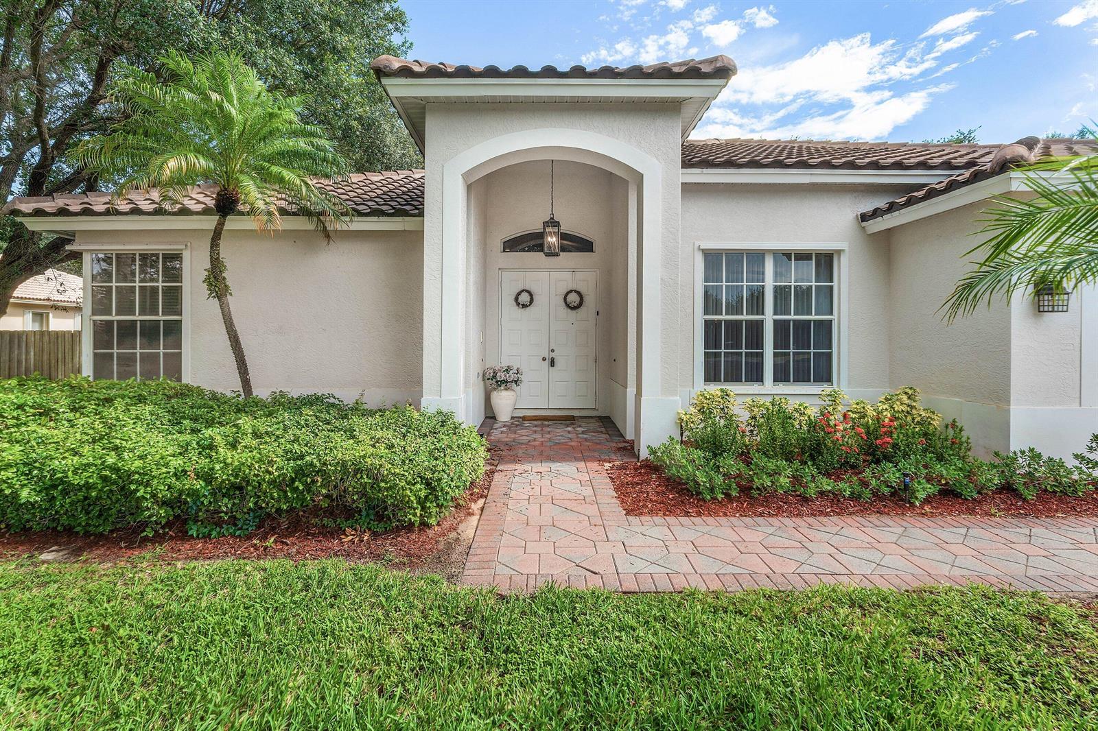 A single-story house with a white stucco facade, tiled roof, and a brick walkway entrance — 4378 Danielson Drive, Lake Worth FL 33467, LAKE WORTH, FL