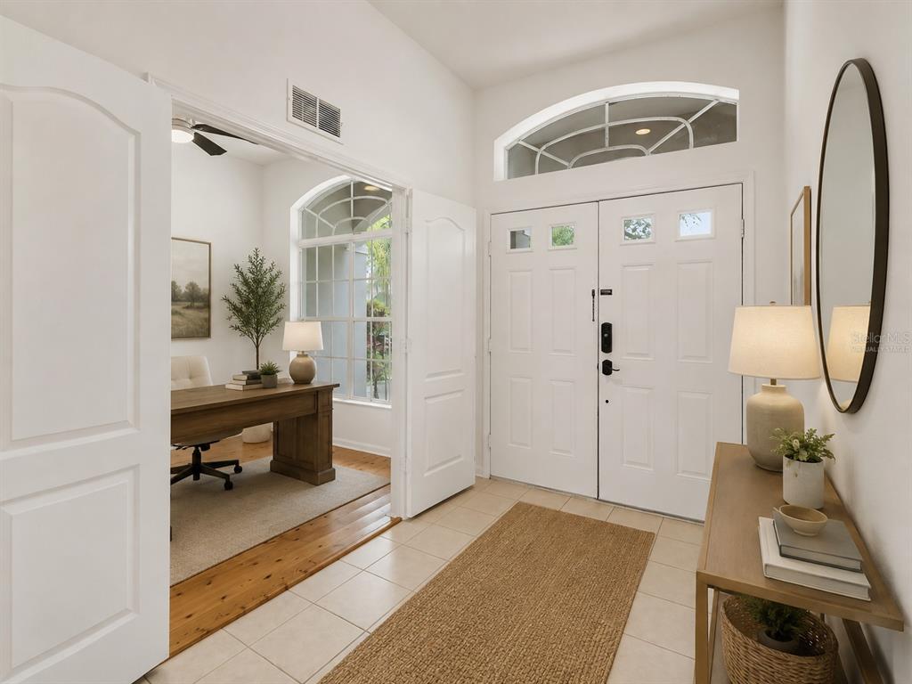 A bright entryway with tile floors leads into a home office with wood flooring — 2041 HEARTLAND CIRCLE, VALRICO, FL
