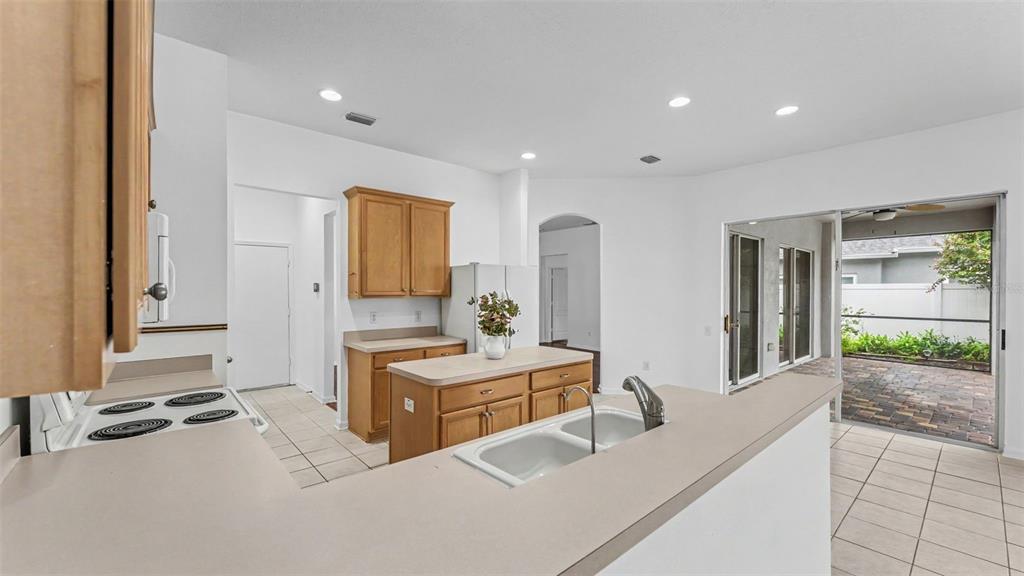 A kitchen features light wood cabinets, a central island, and a sliding door to a patio — 2041 HEARTLAND CIRCLE, VALRICO, FL