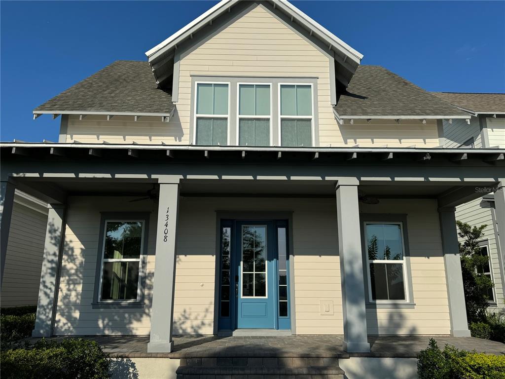 A two-story house with light siding, a covered front porch, and a blue front door — 13408 BEEBE ALLEY, ORLANDO, FL