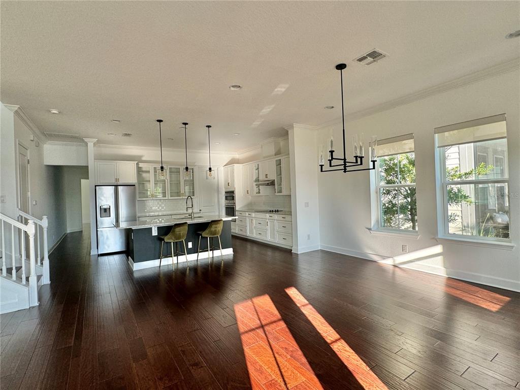 A kitchen with white cabinets, a dark island, and hardwood floors opens to a living area — 13408 BEEBE ALLEY, ORLANDO, FL