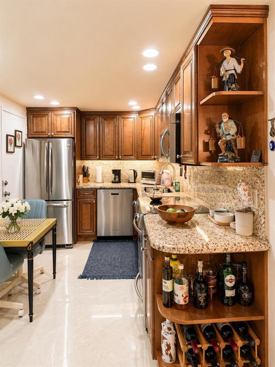A kitchen with wood cabinets, granite countertops, stainless steel appliances, and a small dining area — 1985 S Ocean Drive, Hallandale Beach FL 33009, HALLANDALE BEACH, FL