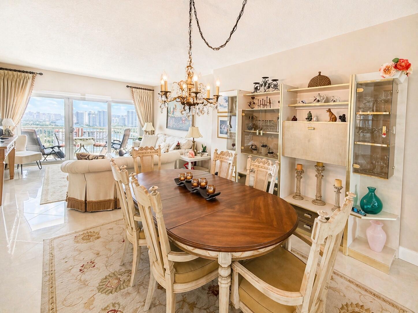 A dining room with a wooden table, chandelier, and a view of city high-rises — 1985 S Ocean Drive, Hallandale Beach FL 33009, HALLANDALE BEACH, FL