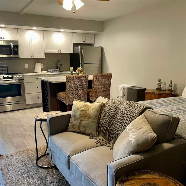 A studio apartment features a kitchen with white cabinets, stainless appliances, and a living area — 3700 S ATLANTIC AVENUE UNIT 102, NEW SMYRNA BEACH, FL