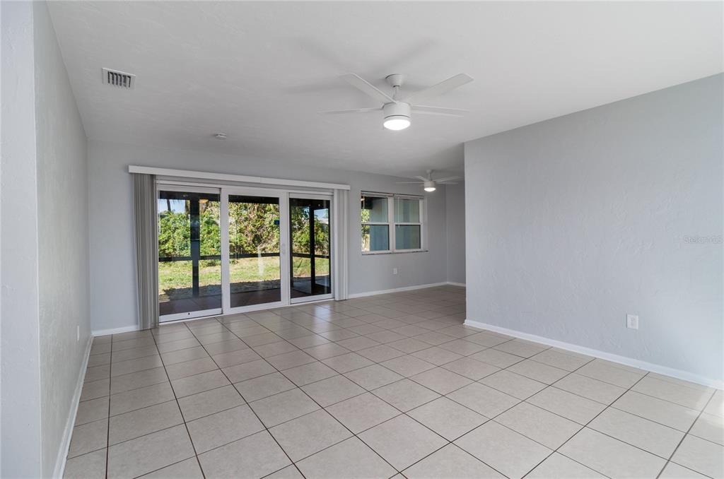 A bright room with light gray walls, tiled floors, a ceiling fan, and sliding glass doors — 2159 FLOYD COURT, PORT CHARLOTTE, FL