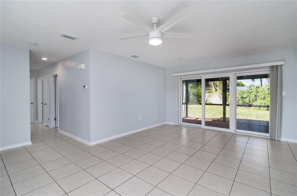 A bright living room features light-colored tile flooring, a ceiling fan, and sliding glass doors — 2159 FLOYD COURT, PORT CHARLOTTE, FL