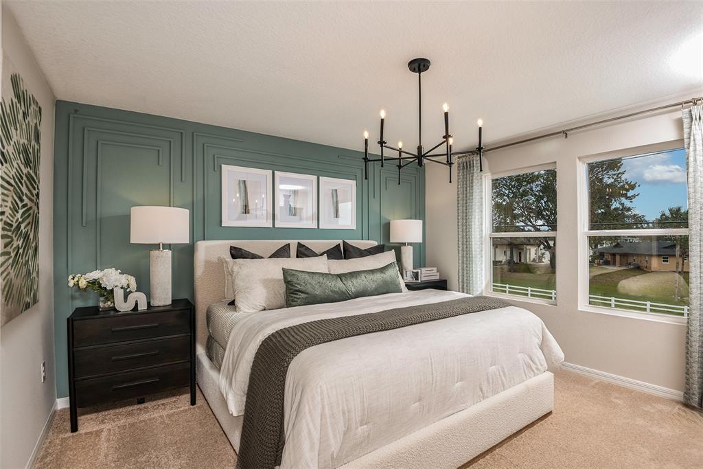 A bedroom features a teal accent wall with molding, a chandelier, and a king-sized bed — 4258 HILLOCK BOULEVARD, HAINES CITY, FL