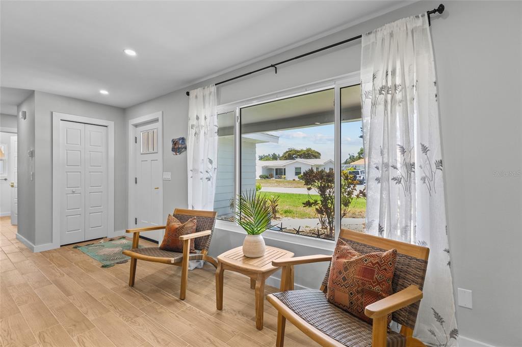 A bright living area features two wooden chairs, a small table, and a large window — 7307 14TH AVENUE W, BRADENTON, FL