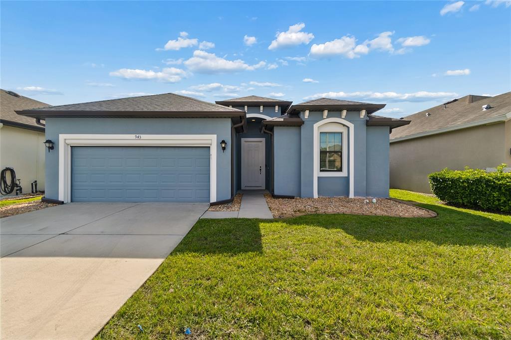 A blue single-story house with a two-car garage and a front walkway — 943 OLD WINDSOR WAY, SPRING HILL, FL