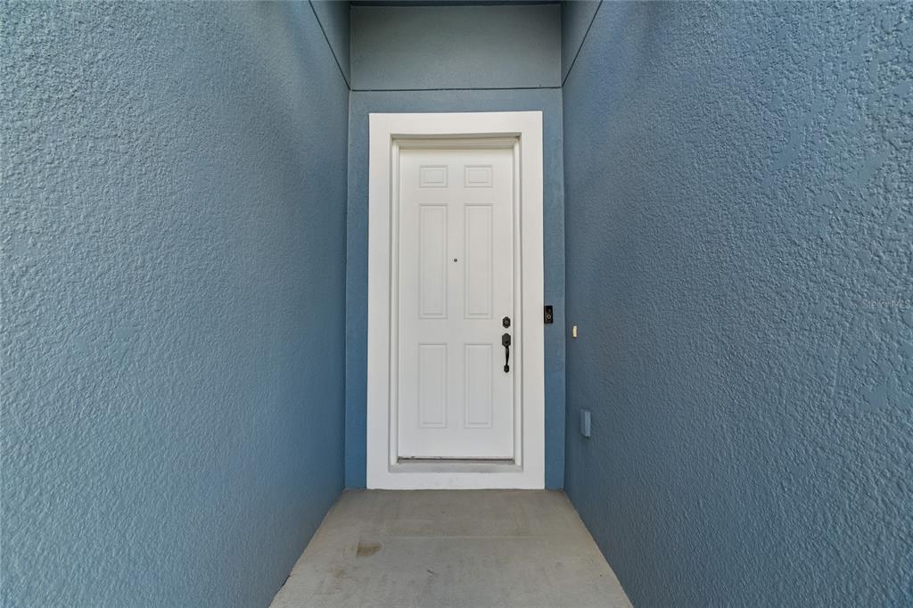 A white front door is set within a recessed entryway with blue textured walls — 943 OLD WINDSOR WAY, SPRING HILL, FL