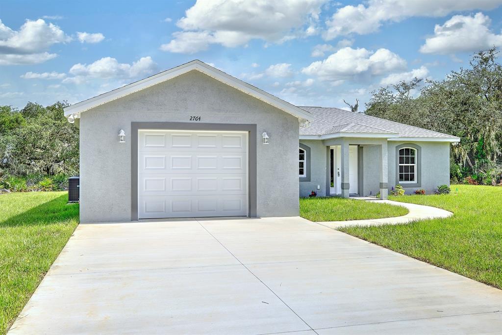 A single-story house with a gray stucco exterior, a one-car garage, and a concrete driveway — 2764 W SOMERSET ROAD, AVON PARK, FL