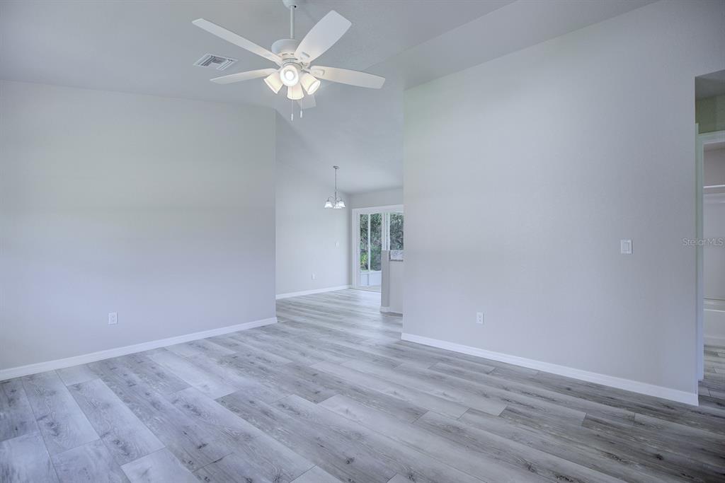 A spacious living area features light gray walls, a ceiling fan, and wood-look laminate flooring — 2764 W SOMERSET ROAD, AVON PARK, FL