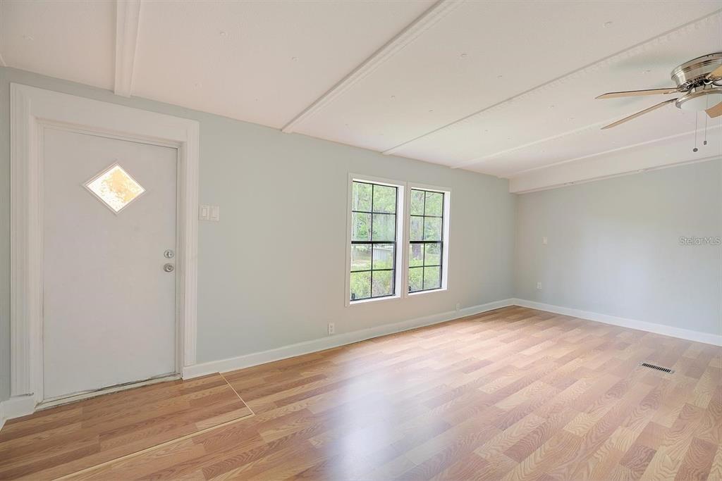 An empty room with light blue walls, wood-look flooring, a ceiling fan, and a door — 4555 S LEISURE BOULEVARD, LECANTO, FL