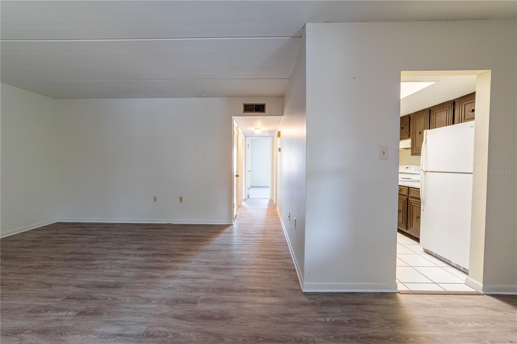 A view of a living area with wood-look flooring leading to a hallway and kitchen — 4718 JOSEPH COURT UNIT 220, TAMPA, FL