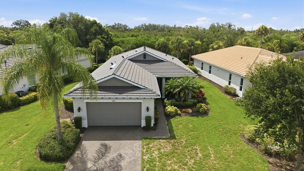 An aerial view of a house with a tiled roof, screened patio, and fenced backyard — 5029 LAKE OVERLOOK AVENUE, BRADENTON, FL