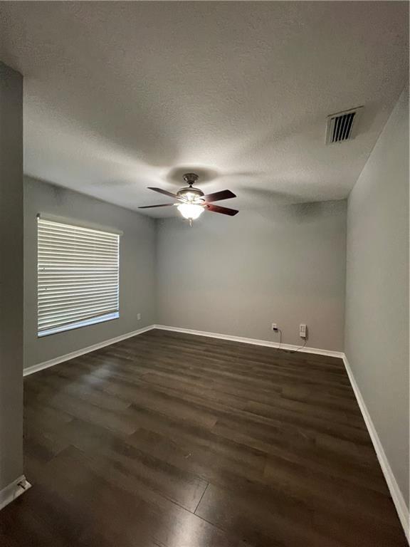 An empty bedroom features light gray walls, dark wood-look flooring, and a ceiling fan — 1435 9th Place, Vero Beach FL 32960, VERO BEACH, FL