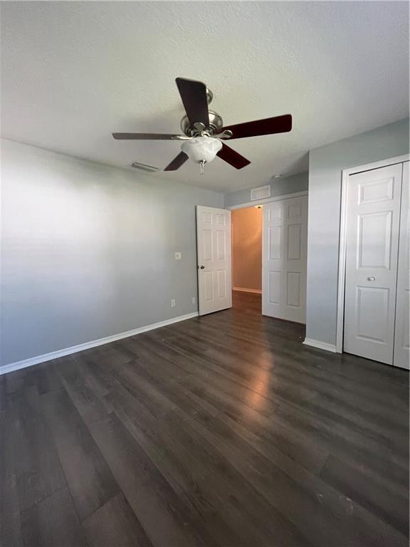 A bedroom with gray walls, dark wood-look flooring, a ceiling fan, and white doors — 1435 9th Place, Vero Beach FL 32960, VERO BEACH, FL