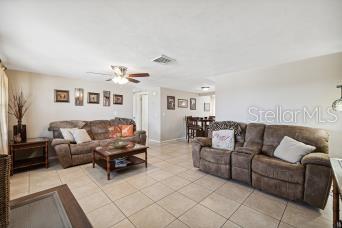 A living room features beige tile floors, brown reclining sofas, and a wooden coffee table — 4408 RUDDER WAY, NEW PORT RICHEY, FL