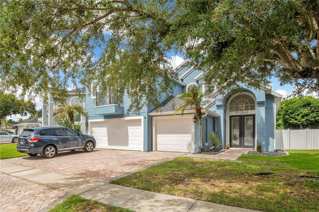 A blue two-story house features a brick driveway, a three-car garage, and a front entryway — 2842 EGRETS LANDING DRIVE, LAKE MARY, FL