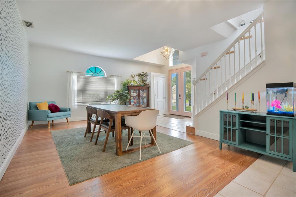A dining room features a wooden table, a blue accent chair, and a staircase — 2842 EGRETS LANDING DRIVE, LAKE MARY, FL