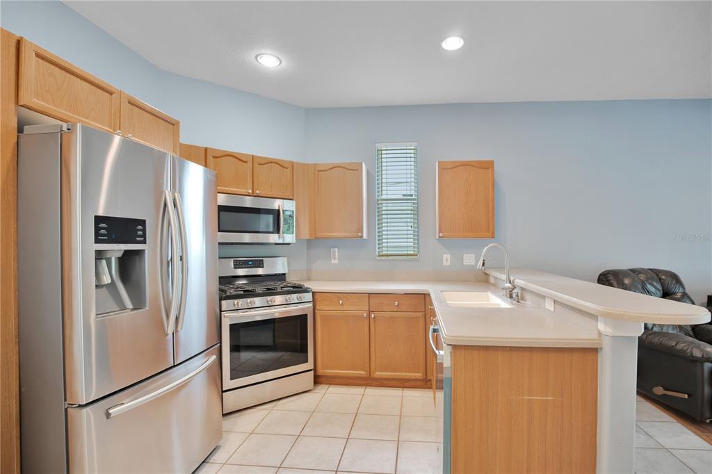 A kitchen features light wood cabinets, stainless steel appliances, and a breakfast bar — 2842 EGRETS LANDING DRIVE, LAKE MARY, FL