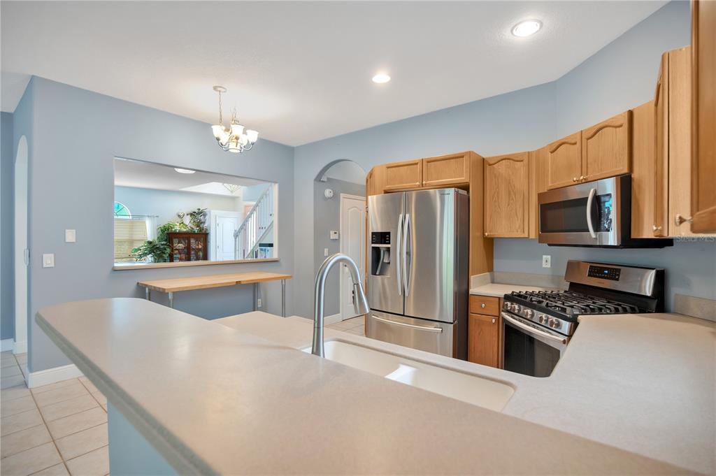 A kitchen features light blue walls, wood cabinets, stainless steel appliances, and a breakfast bar — 2842 EGRETS LANDING DRIVE, LAKE MARY, FL
