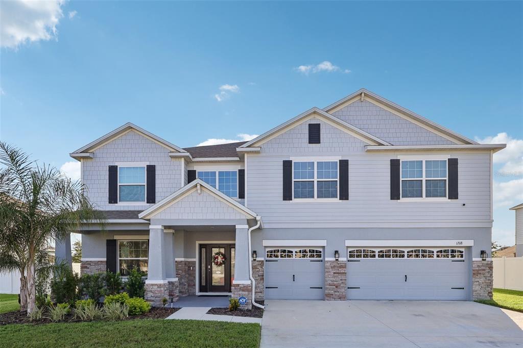 A two-story suburban house with light gray siding, stone accents, and a three-car garage — 1208 HILLBRIDGE DRIVE, HAINES CITY, FL
