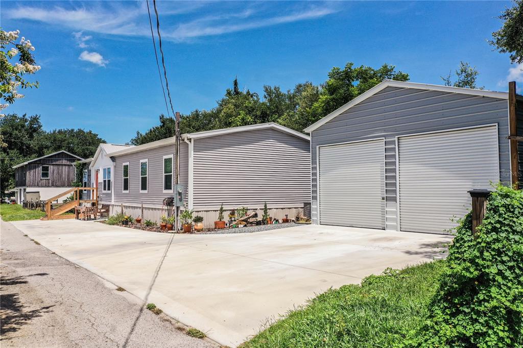 A light gray manufactured home sits next to a detached two-car garage with concrete driveway — 950 LAKE COVE TRAIL, LAKELAND, FL