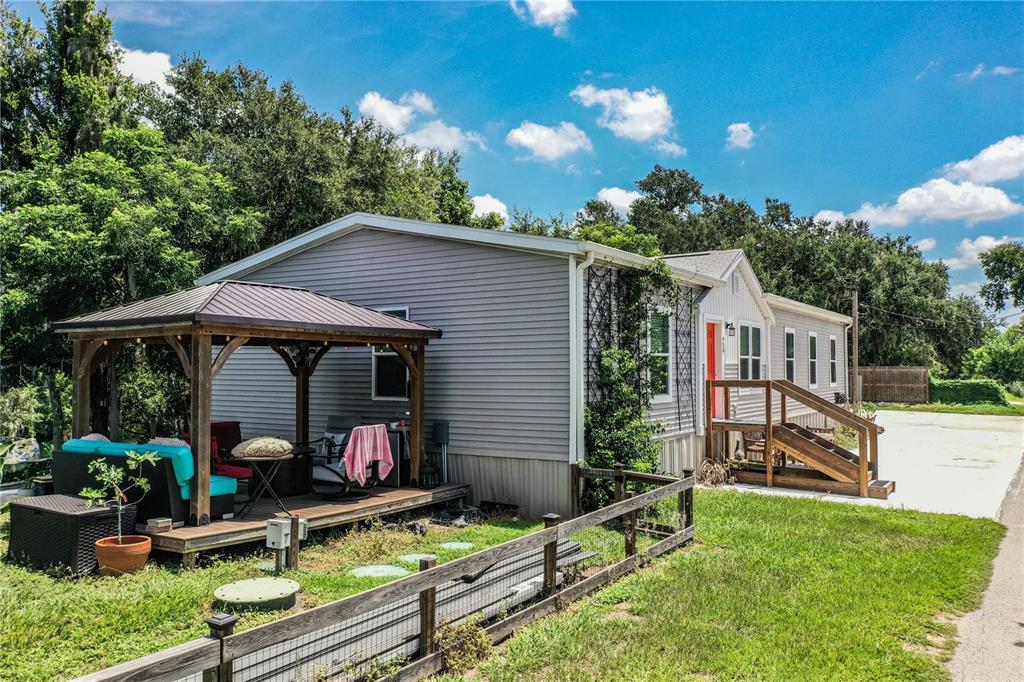 A light gray manufactured home features a wooden gazebo on a deck and a staircase entrance — 950 LAKE COVE TRAIL, LAKELAND, FL