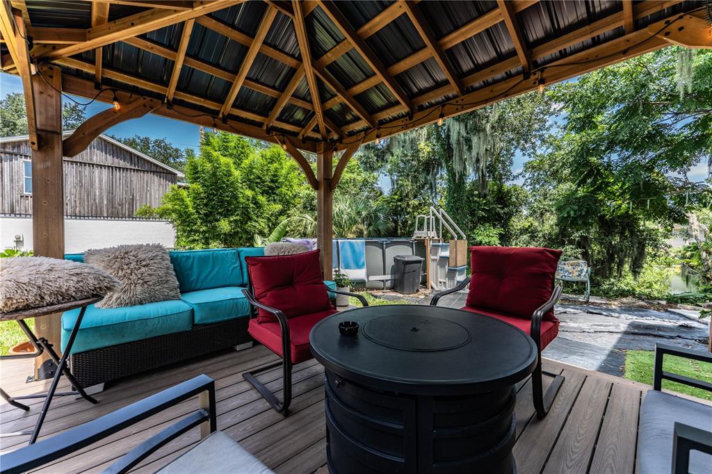 A wooden gazebo covers a deck with a fire pit, red chairs, and a blue sofa — 950 LAKE COVE TRAIL, LAKELAND, FL