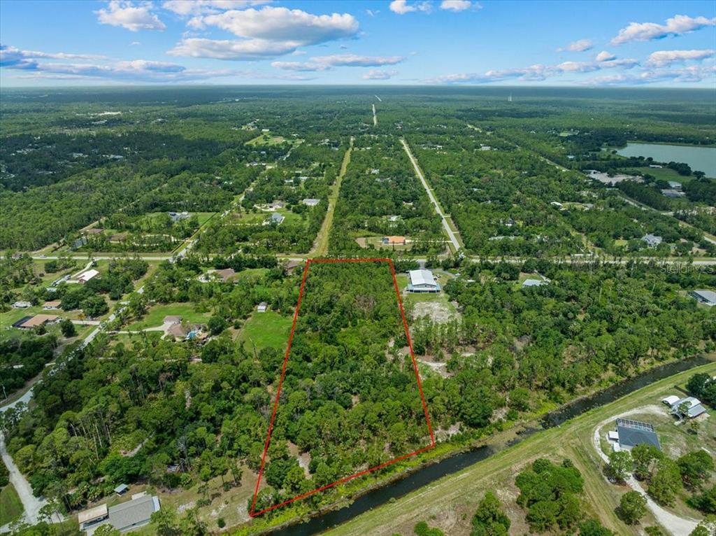 An aerial view shows a rectangular, wooded lot outlined in red near a canal — N CHAMBERLAIN BOULEVARD, NORTH PORT, FL