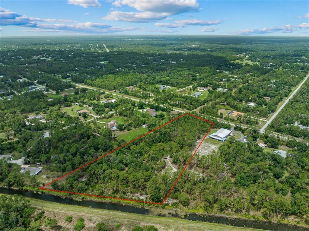 An aerial view shows a rectangular plot of land outlined in red near a canal — N CHAMBERLAIN BOULEVARD, NORTH PORT, FL