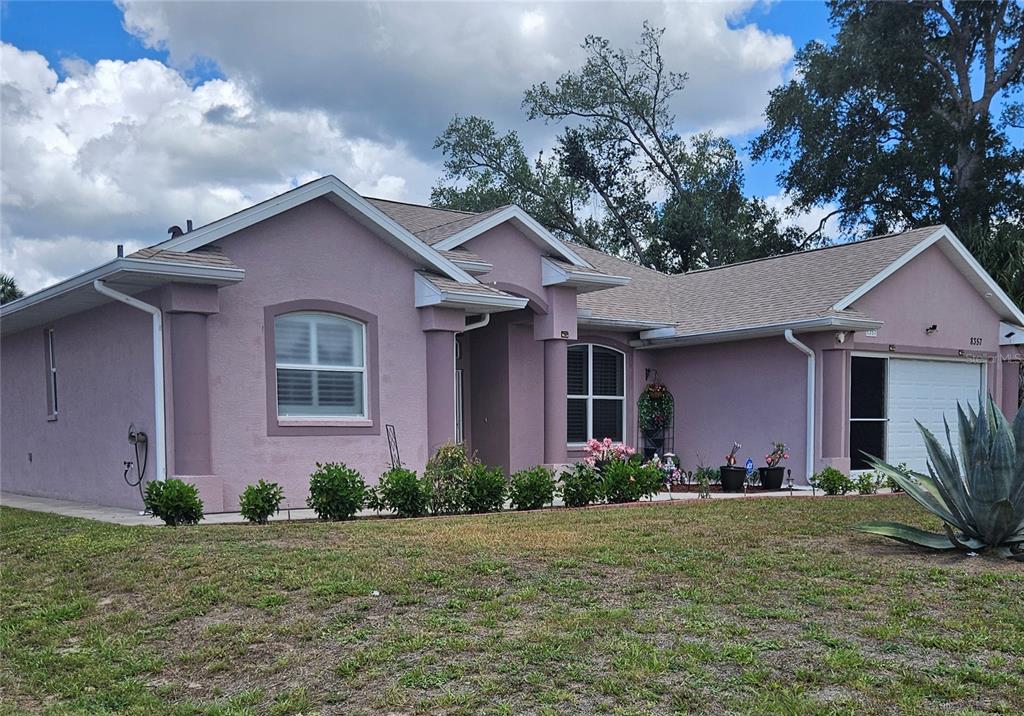 A single-story pink stucco house with a shingled roof and a front-facing garage — 8357 DENARGO ROAD, NORTH PORT, FL